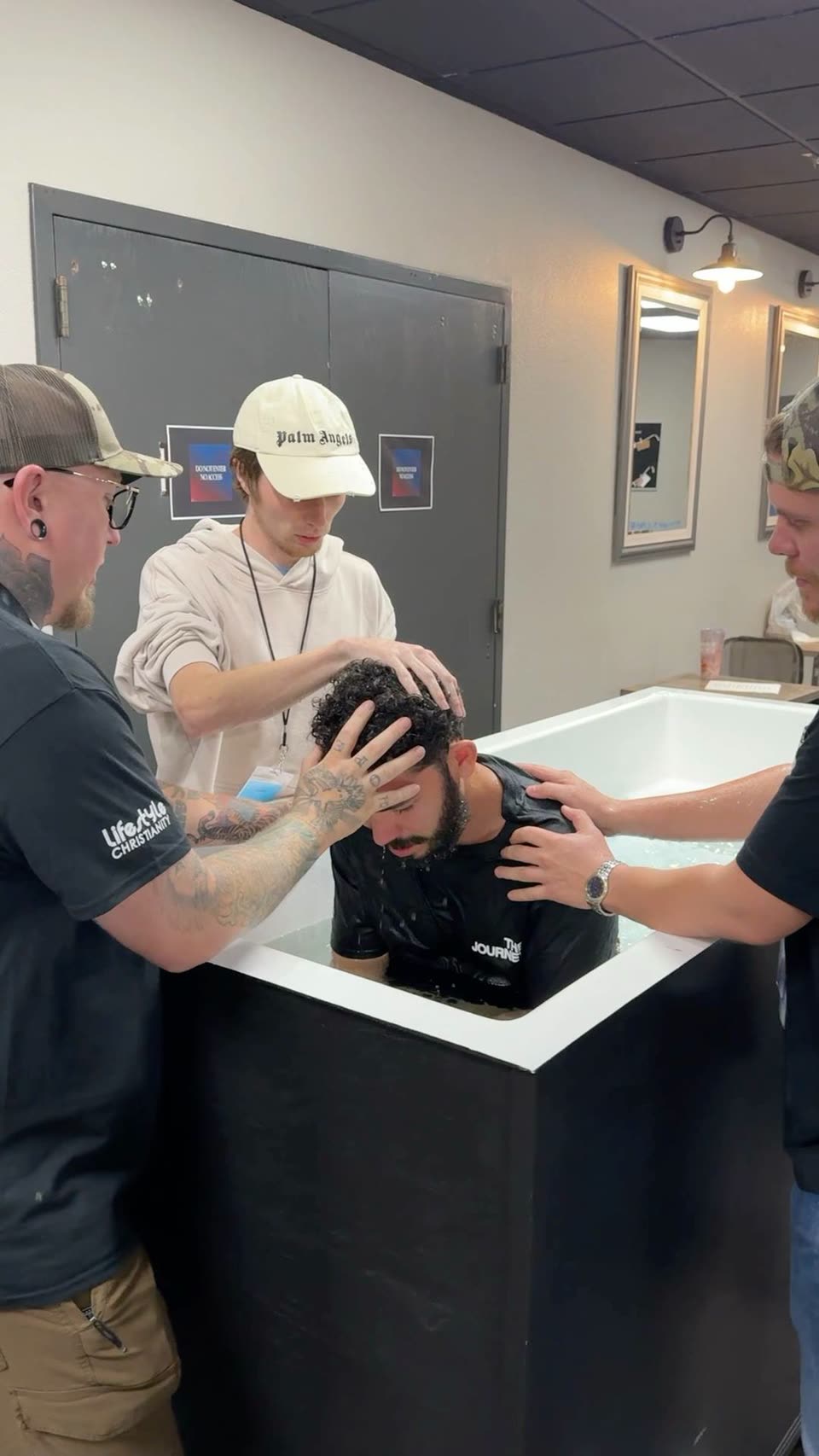 Andrew in a baptism pool while three men pray with him