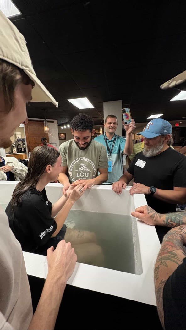 Hailey in a baptism pool holding Andrew's hand