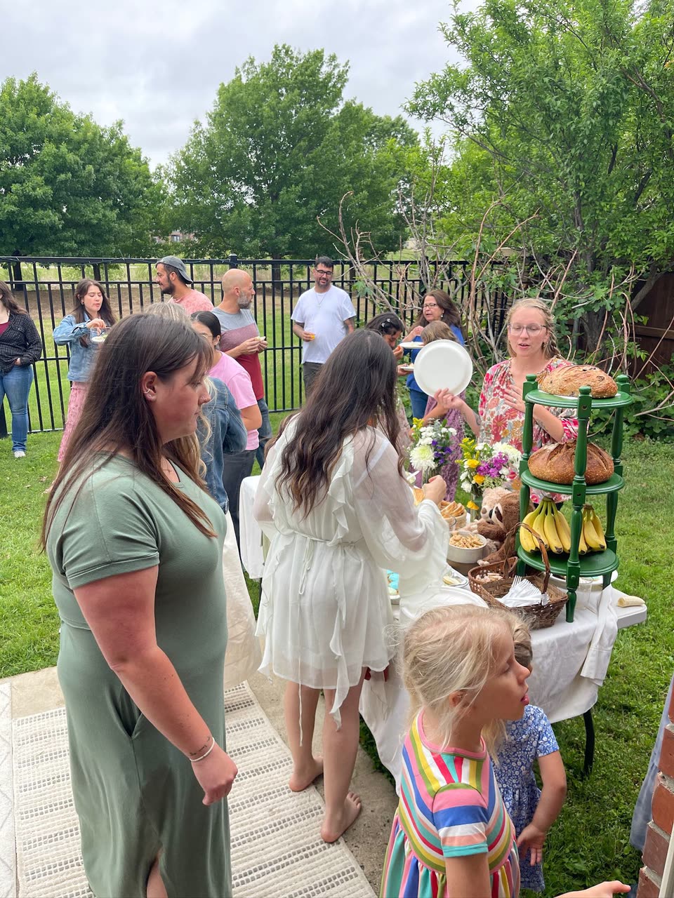 Adults and children talking around an outdoor food table