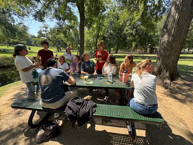 Friends talking together around a park picnic table