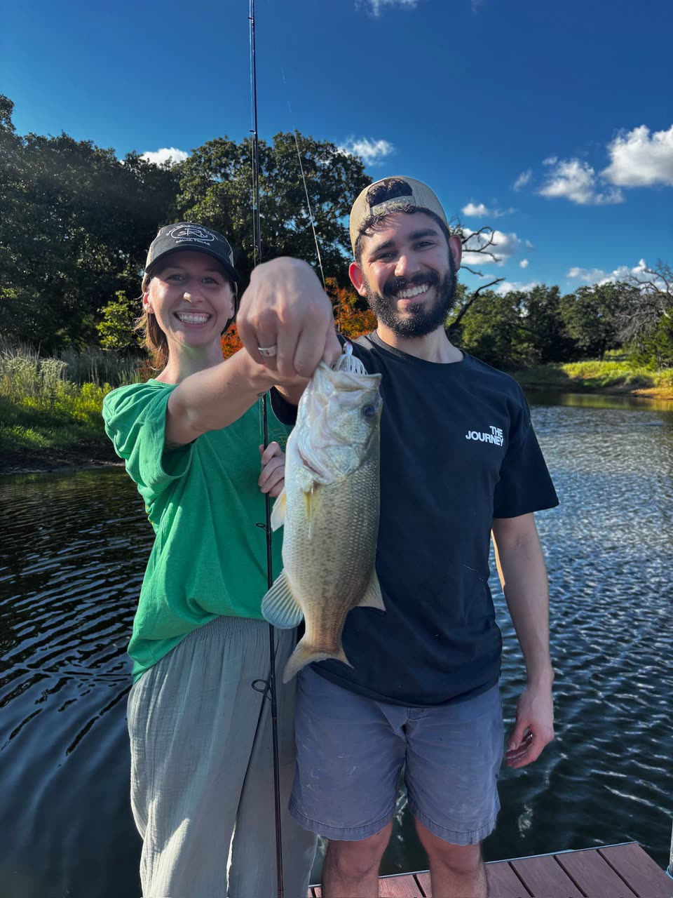 Andrew and Hailey smiling together beside a lake after fishing
