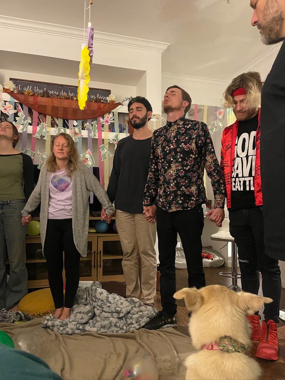 A group standing together in prayer inside a decorated home